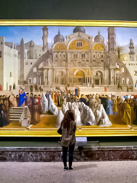 Visitor admiring a large painting at Brera Gallery, Milan.