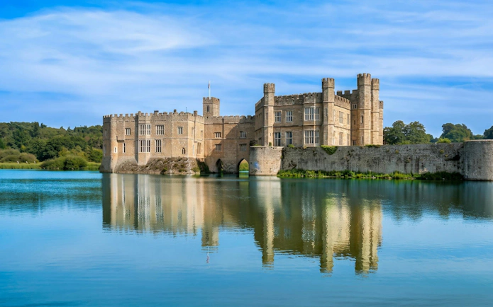 Leeds Castle in Kent, England, surrounded by a moat and lush greenery.
