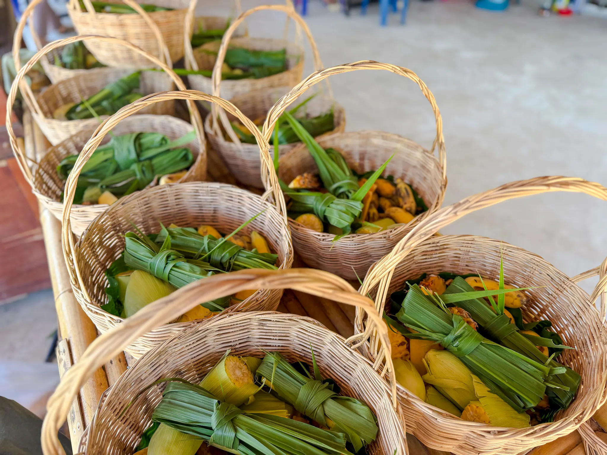 Wicker baskets filled with banana leaves and fruit at Krabi Elephant Local Project workshop.