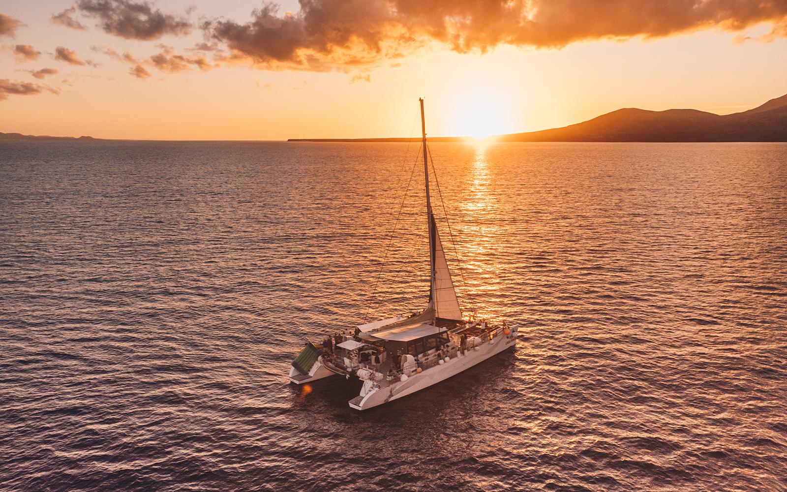 Catamaran sailing at sunset in Lanzarote for dolphin watching.