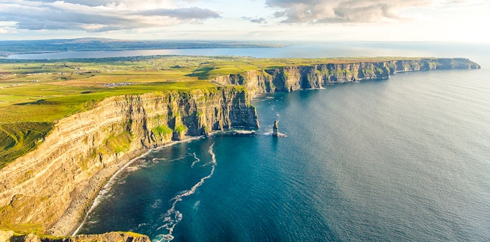 Aerial view of the Cliffs of Moher, Ireland, with ocean and green landscape.