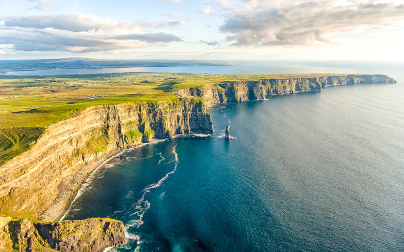 Aerial view of the Cliffs of Moher, Ireland, with ocean and green landscape.