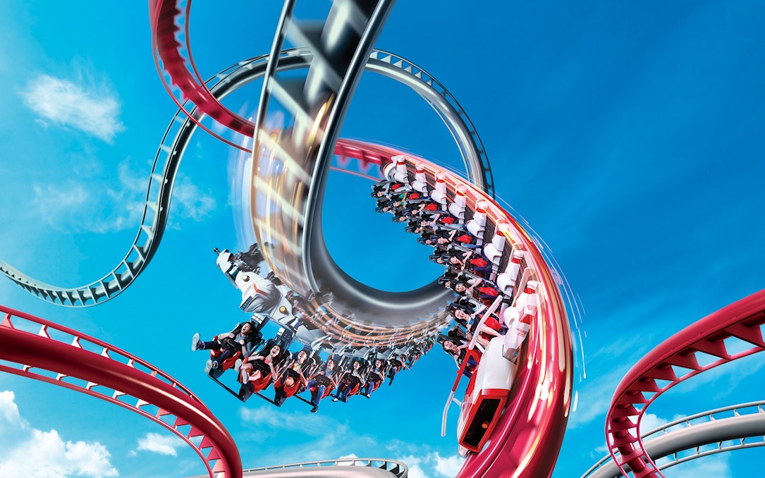 Rollercoaster loop at Universal Studios Singapore against blue sky.