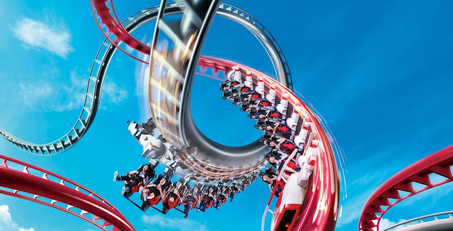 Rollercoaster loop at Universal Studios Singapore against blue sky.
