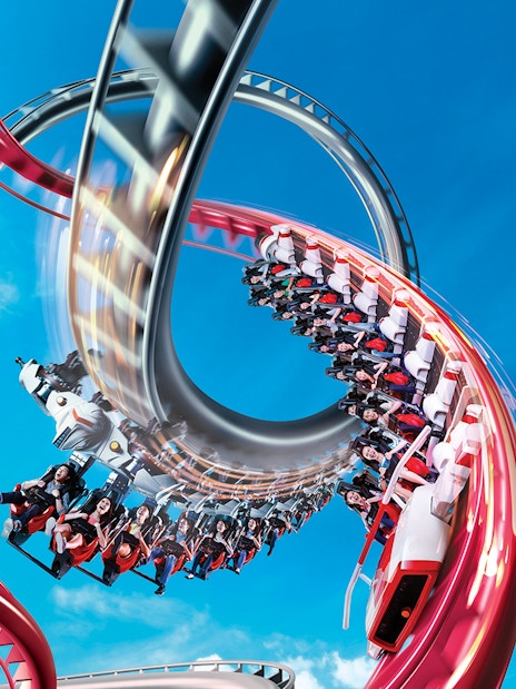 Rollercoaster loop at Universal Studios Singapore against blue sky.