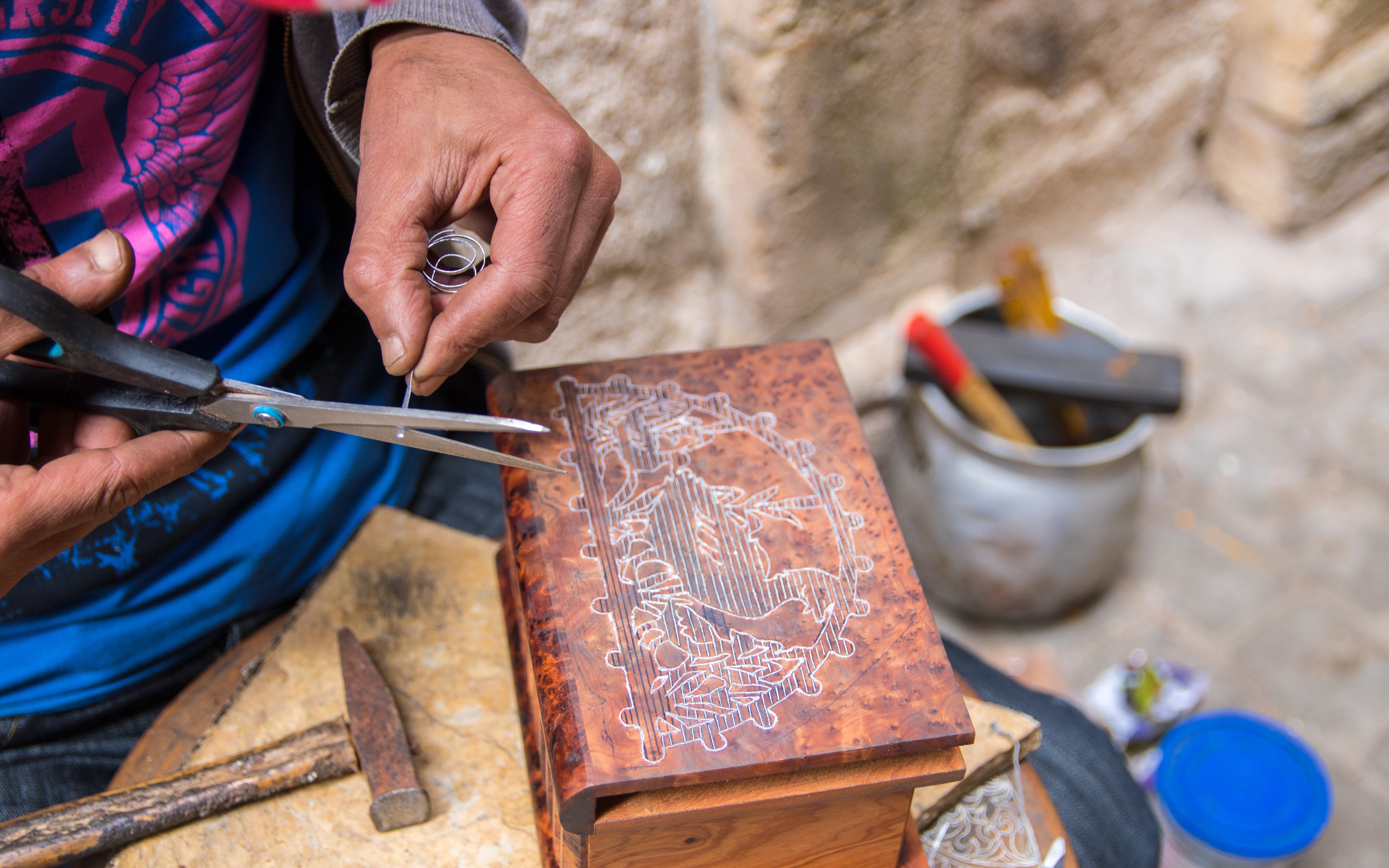 Artist crafting intricate design on wooden box at artisan shop in Chefchaouen.