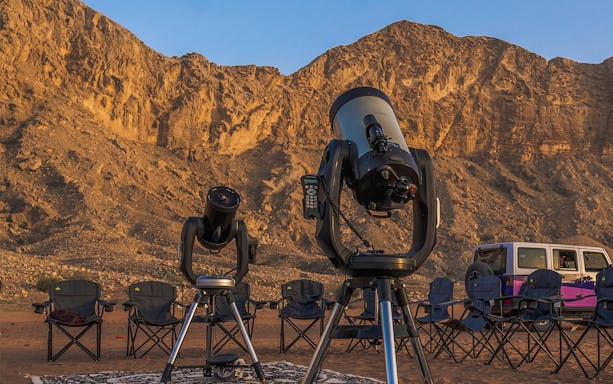 Telescopes set up for stargazing at Mleiha Space Camp with desert mountains in the background.