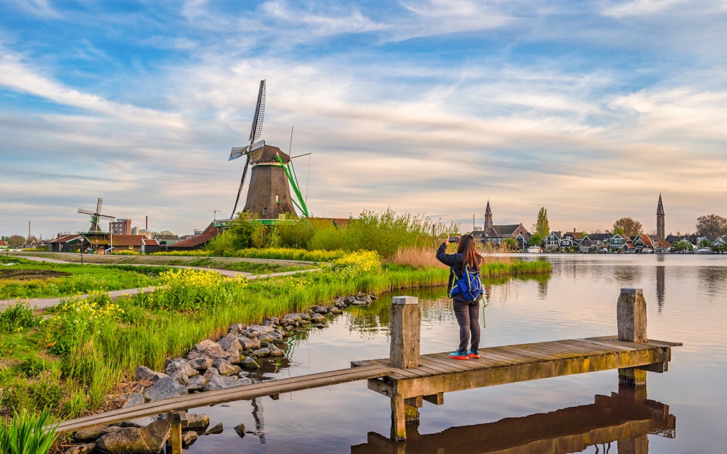 Tourist photographing Dutch windmill at Zaanse Schans Village, Amsterdam, Netherlands.