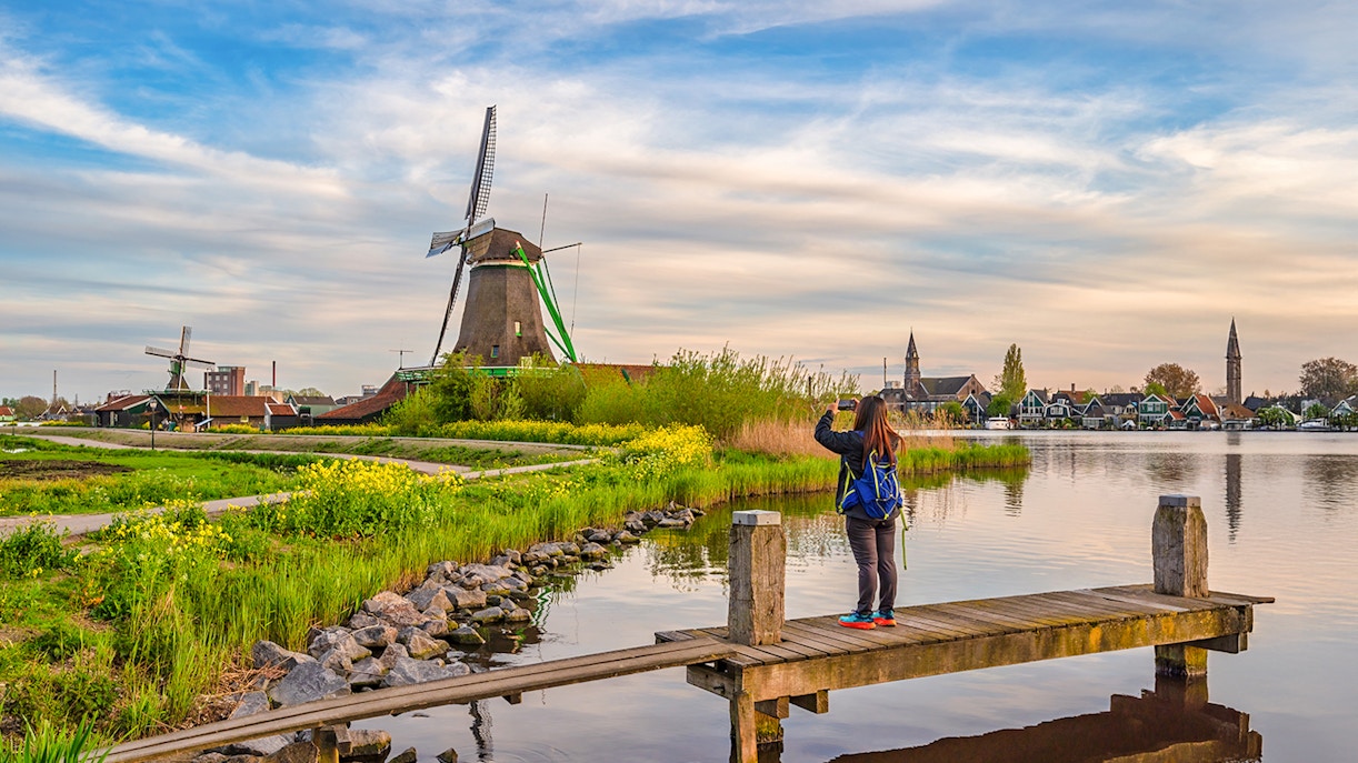 Tourist photographing Dutch windmill at Zaanse Schans Village, Amsterdam, Netherlands.