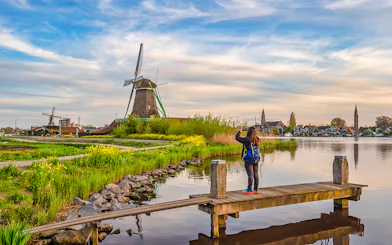 Tourist photographing Dutch windmill at Zaanse Schans Village, Amsterdam, Netherlands.