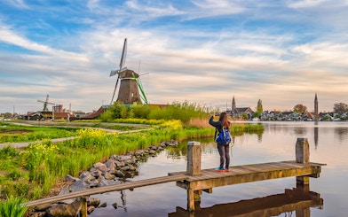 Tourist photographing Dutch windmill at Zaanse Schans Village, Amsterdam, Netherlands.