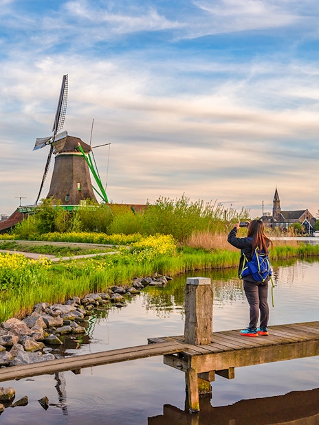 Tourist photographing Dutch windmill at Zaanse Schans Village, Amsterdam, Netherlands.