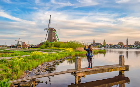 Tourist photographing Dutch windmill at Zaanse Schans Village, Amsterdam, Netherlands.