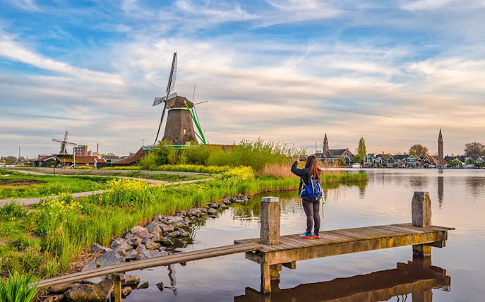 Tourist photographing Dutch windmill at Zaanse Schans Village, Amsterdam, Netherlands.
