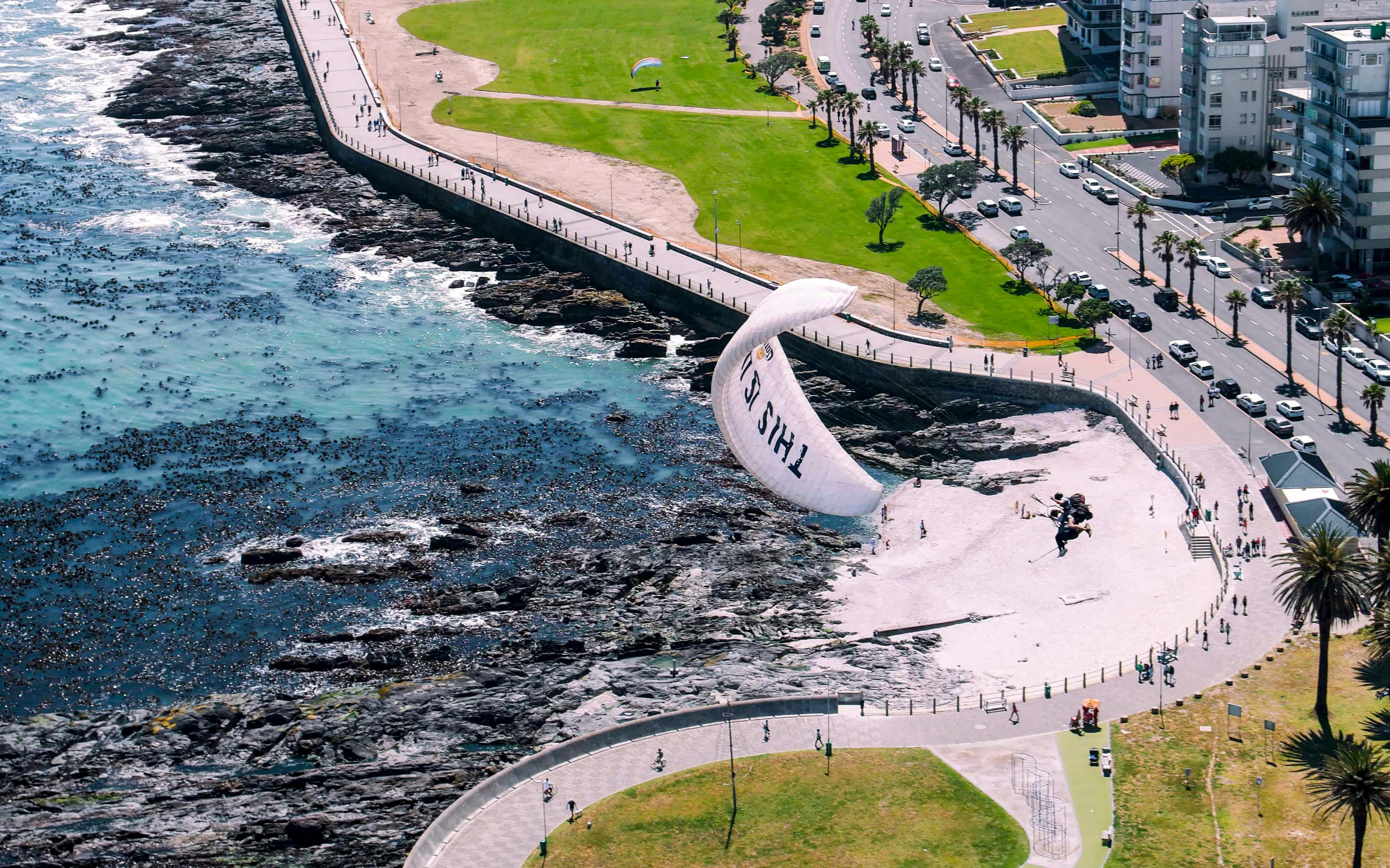 Aerial view of tandem paragliding over Cape Town coastline.