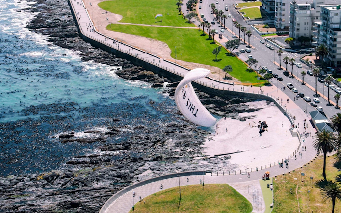Aerial view of tandem paragliding over Cape Town coastline.