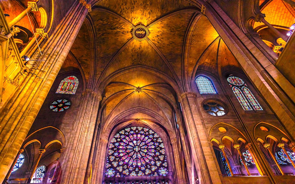 Notre-Dame Cathedral interior with stained glass windows and vaulted ceilings, Paris tour.