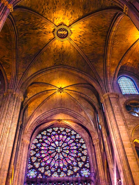 Notre-Dame Cathedral interior with stained glass windows and vaulted ceilings, Paris tour.
