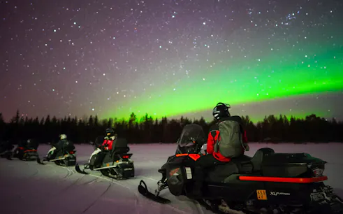 Snowmobilers viewing Northern Lights in Rovaniemi.