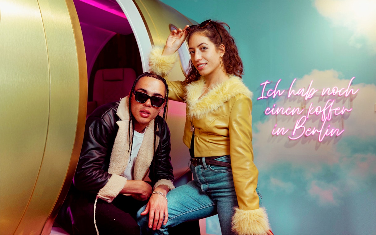 Visitors posing at The Upside Down Berlin with neon sign in background.