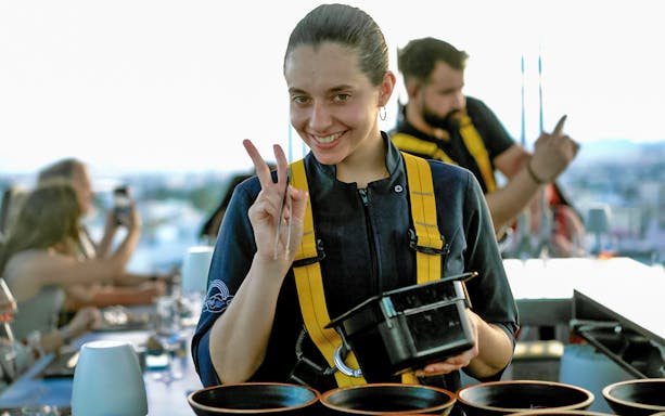 Person smiling and gesturing peace sign during Dinner in the Sky Athens experience.