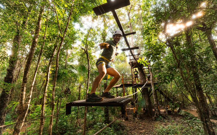 Adventurer crossing a rope bridge in Cancun Extreme Adventuring Park.