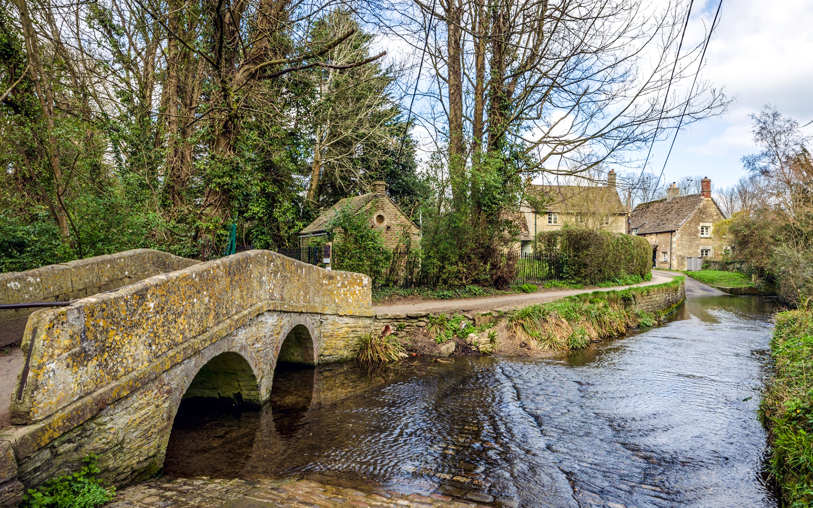 Stone bridge over a stream in the historic village of Lacock, Wiltshire, England.