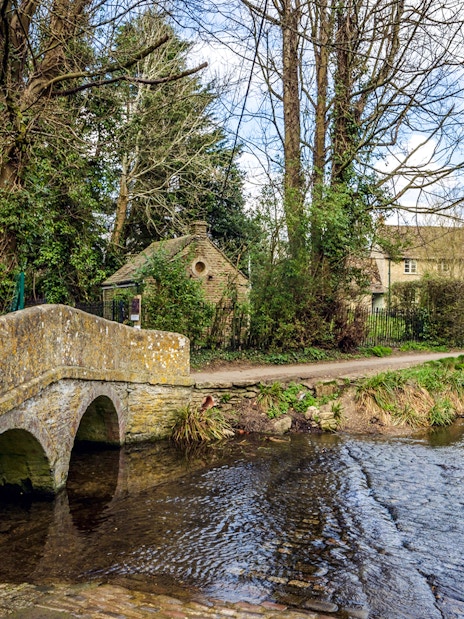Stone bridge over a stream in the historic village of Lacock, Wiltshire, England.