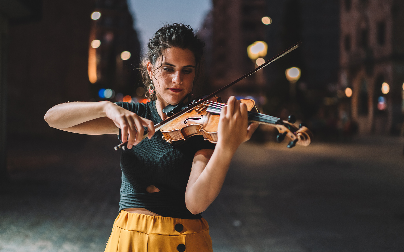 Street musician playing violin at night in Barcelona.