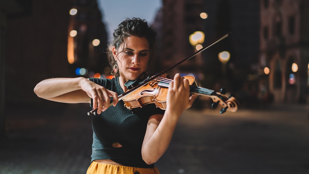 Street musician playing violin at night in Barcelona.