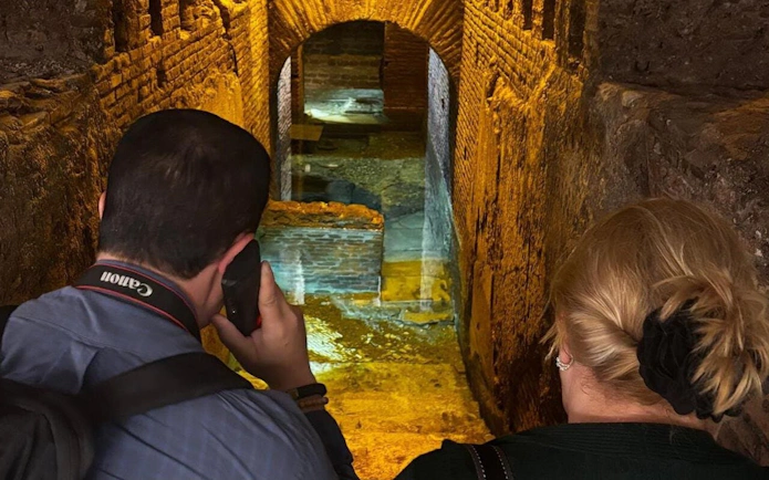 Visitors exploring subterranean aqueducts beneath Piazza Navona, Rome.