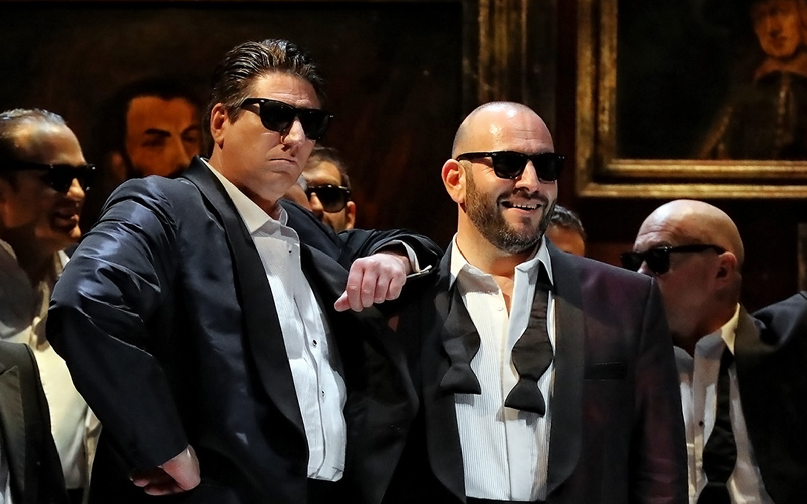 Performers in tuxedos and sunglasses during a Rigoletto show production.