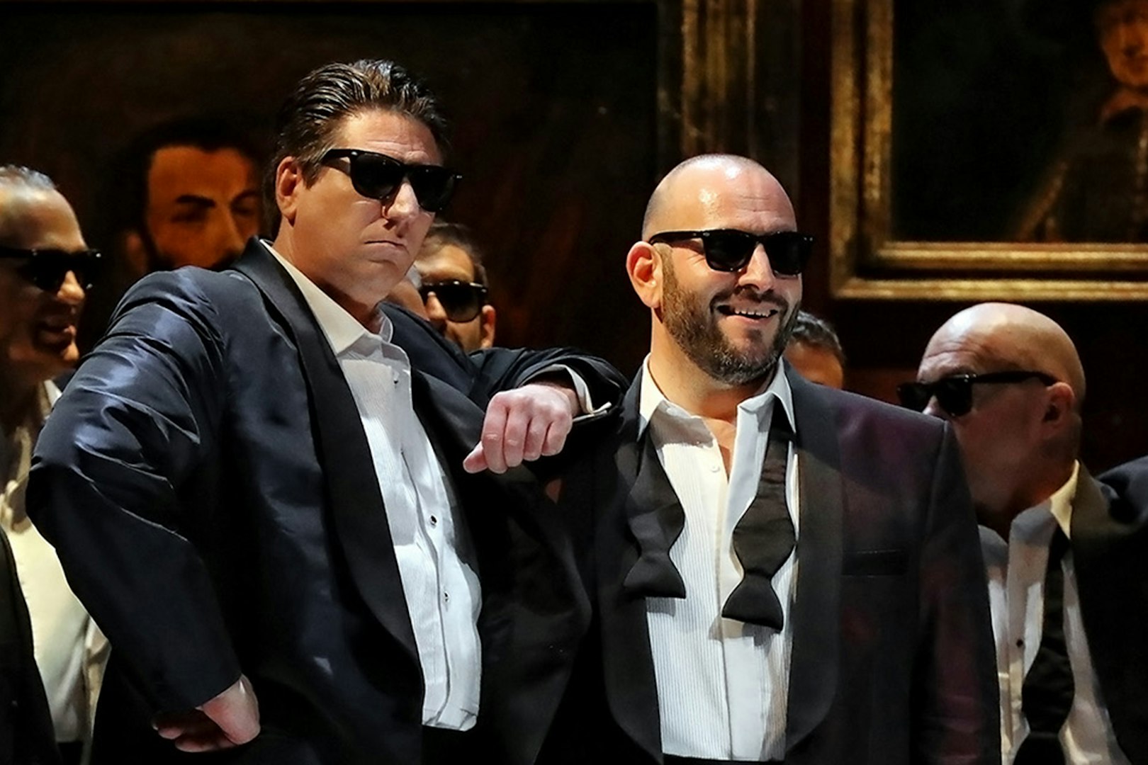 Performers in tuxedos and sunglasses during a Rigoletto show production.