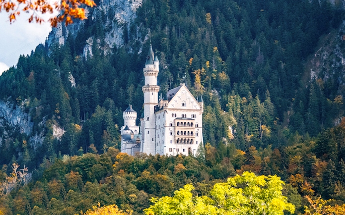 Neuschwanstein Castle surrounded by forested hills in Bavaria, Germany.