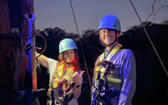 Participants ready for night zipline adventure with helmets and harnesses.