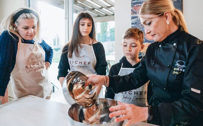 Participants learning to mix ingredients in a pizza and tiramisù cooking class.