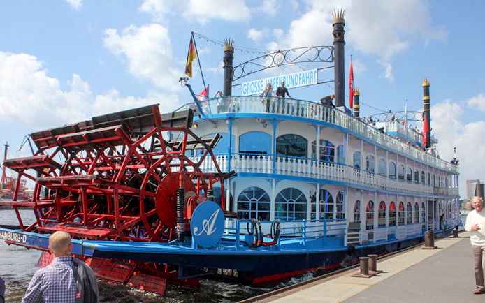 Paddle steamer docked in Hamburg, Germany, with passengers on deck.