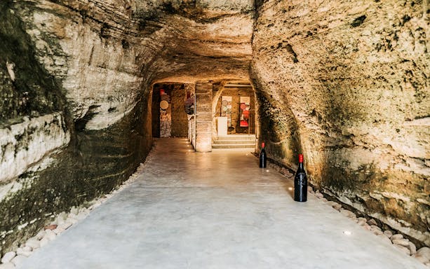 Wine cellar with stone walls and large bottles, part of an explore tasting tour.