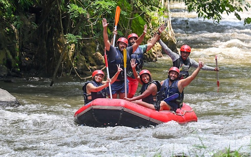 Group rafting on Ayung River in Ubud, wearing helmets and life vests, surrounded by lush greenery.