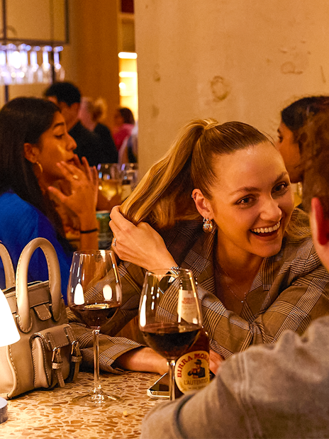 People enjoying drinks and conversation at a lively bar.