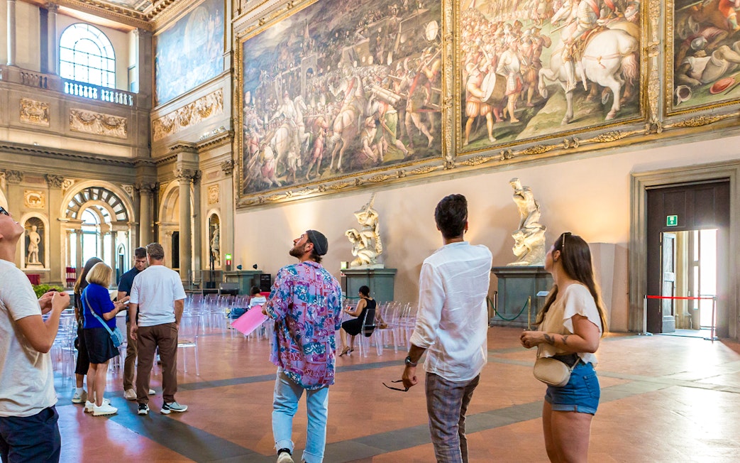 Visitors admiring artwork in Palazzo Vecchio museum, Florence, Italy.
