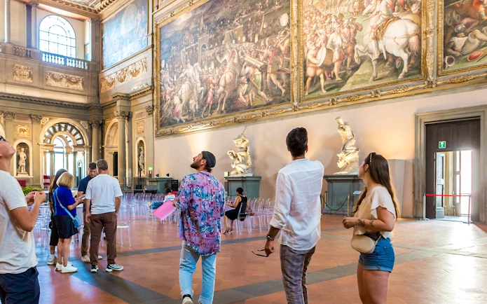 Visitors admiring artwork in Palazzo Vecchio museum, Florence, Italy.