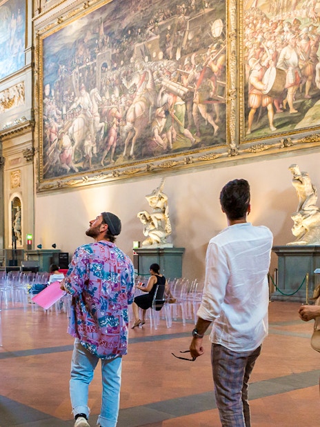 Visitors admiring artwork in Palazzo Vecchio museum, Florence, Italy.