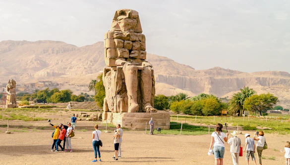Tourists exploring the Colossi of Memnon near Luxor Temple, Egypt.