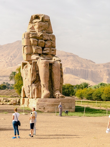 Tourists exploring the Colossi of Memnon near Luxor Temple, Egypt.