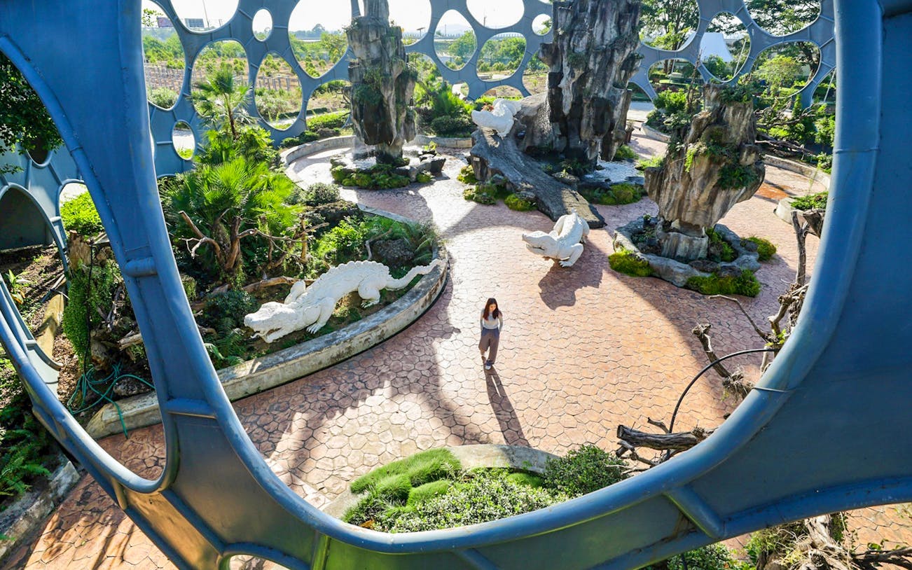 Visitor walking through Flower Land Pattaya with sculptures and unique architecture.