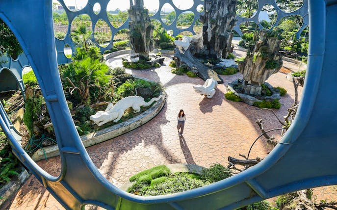 Visitor walking through Flower Land Pattaya with sculptures and unique architecture.