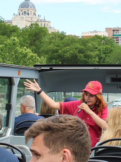 Guide speaking on Madrid Big Bus top deck with Almudena Cathedral in background.