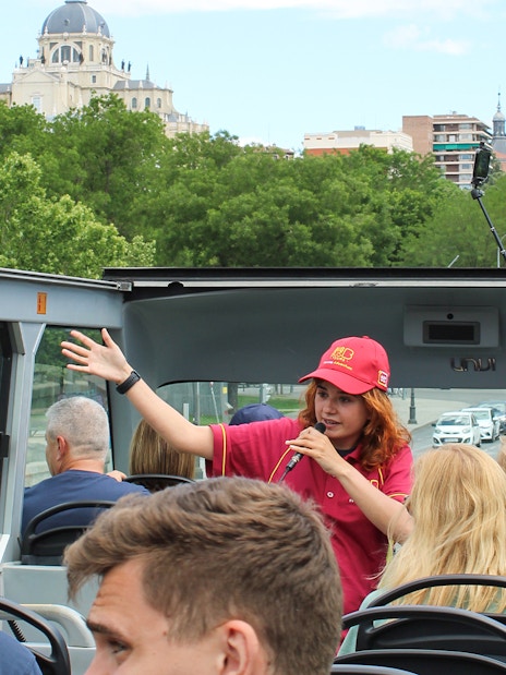 Guide speaking on Madrid Big Bus top deck with Almudena Cathedral in background.