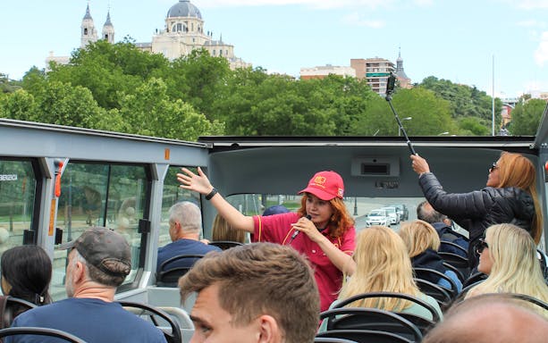 Guide speaking on Madrid Big Bus top deck with Almudena Cathedral in background.